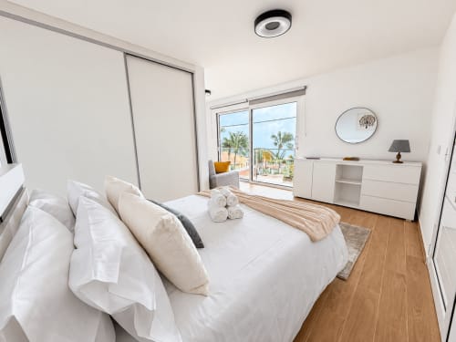 Modern bedroom in Sunshine House 85 villa at Check Madeira, Ribeira Brava, with sea view, white bedding, wooden floors, and