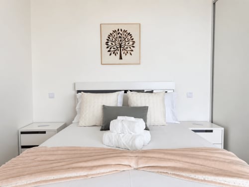 Modern bedroom in Sunshine House 85 villa, Ribeira Brava, with white bed, gray pillows, and tree artwork