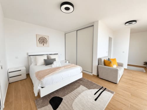 Modern bedroom at Check Madeira villa in Ribeira Brava with white bed, armchair, wooden floors and sea view