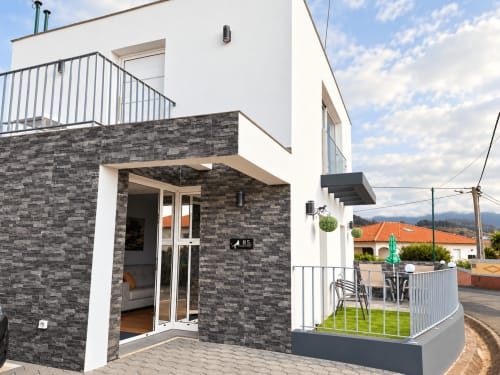 Modern villa entrance at Check Madeira, Ribeira Brava with dark stone facade, white trim, and mountain views