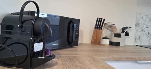 Plan de travail moderne de cuisine équipée d'un micro-ondes Samsung, cafetière, bloc de couteaux et ustensiles dans l'appartement NN Patrimoine