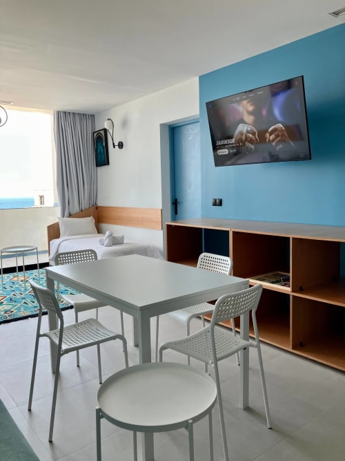 Chambre studio moderne chez SAMYAflat Tanger avec coin repas, lit, mur accentué turquoise et TV écran plat