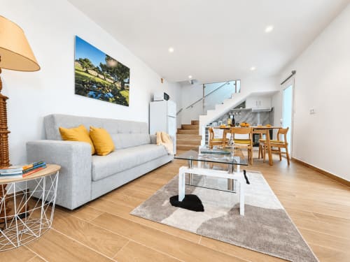 Modern open-plan living area at Check Madeira hotel in Ribeira Brava with gray sofa, wooden dining table, and kitchen