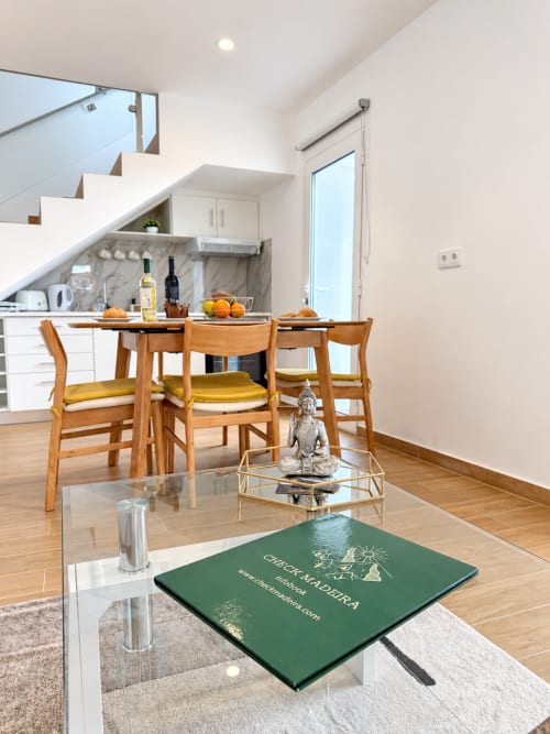 Modern kitchen and dining area at Check Madeira hotel in Ribeira Brava with wooden chairs, white cabinetry, and living room