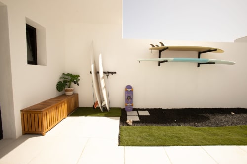 Villa moderna en Fuerteventura con patio, banco de madera, tablas de surf, skateboards y jardín cuidado