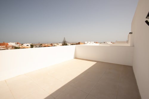 Soleada terraza en azotea de Villa MERAKI en Corralejo, Fuerteventura, con vistas al mar y edificios residenciales