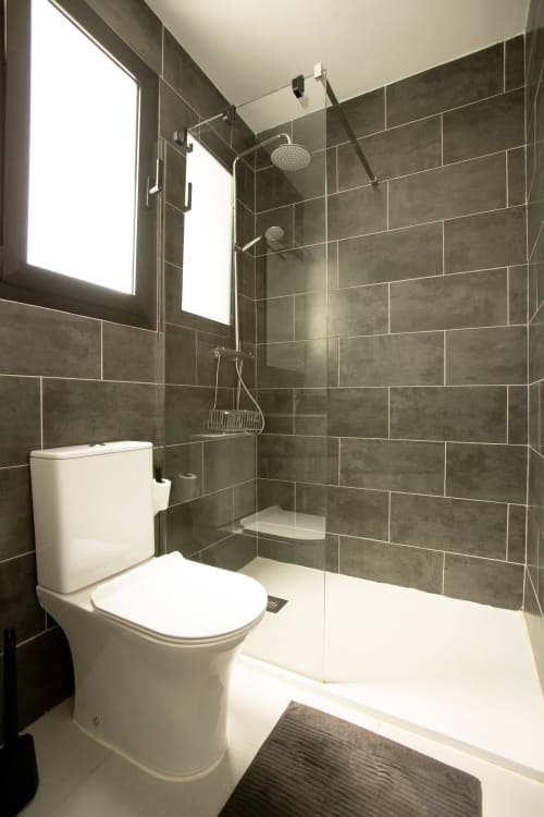 Baño moderno en Villa MERAKI de Gozamena con azulejos grises, inodoro blanco, ducha de cristal y lluvia