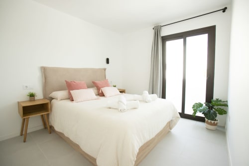 Moderna habitación en Villa MERAKI del hotel Gozamena en Fuerteventura, con cama queen, mesilla de madera y vistas al mar