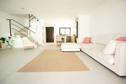 Moderna sala de estar de villa con sofá crema, alfombra beige, muebles de madera y vistas al mar en Gozamena Fuerteventura