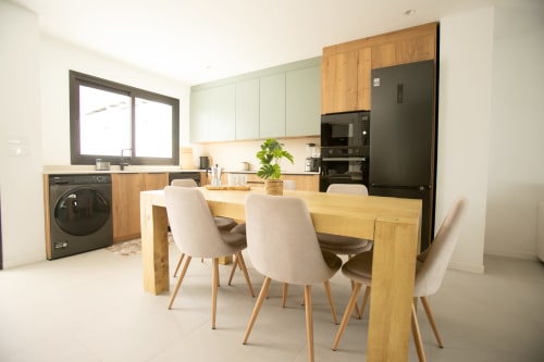 Cocina y comedor modernos en Villa MERAKI con mesa de madera, sillas blancas, electrodomésticos negros y lavadora