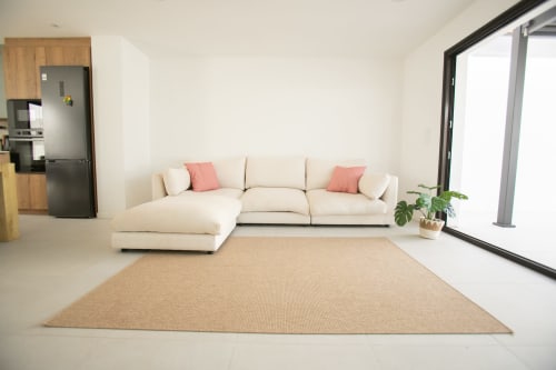 Sala de estar moderna en Villa MERAKI con sofá en L color crema, alfombra natural y vistas al mar, Fuerteventura