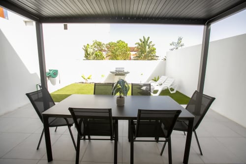 Patio moderno de Villa MERAKI en Fuerteventura con mesa de comedor, tumbonas, césped artificial y vistas al jardín