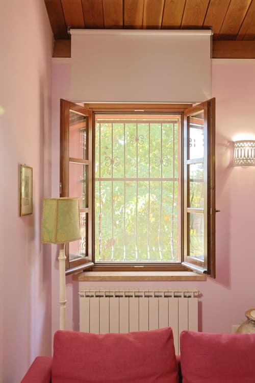 Stanza rosa con finestra in legno, divano rosso e termosifone presso l'hotel boutique La Casa dei Tigli a Cannara
