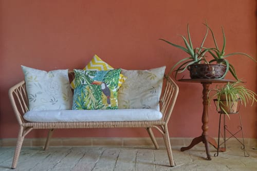 Accogliente angolo lettura a La Casa dei Tigli: divano in rattan intrecciato con cuscini decorati su parete terracotta, portavasi in legno