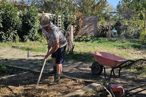 Man digging in garden at Aux Prés Du Berry B&B, Chavin Bonnilly France with wheelbarrow nearby