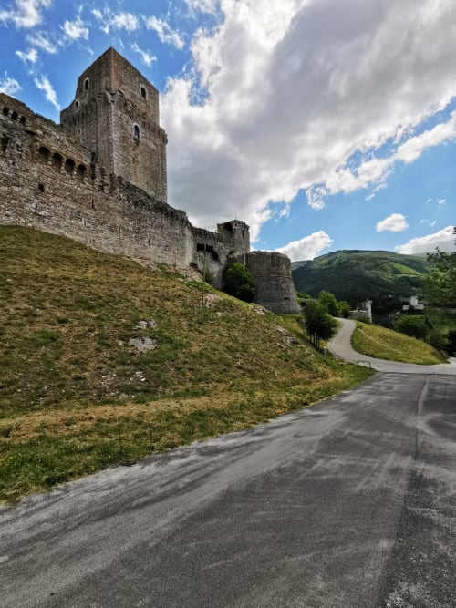 Ruderi di castello medievale con torre in pietra che domina le verdi colline vicino a Cannara, Italia