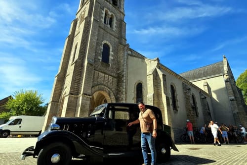 Man with vintage black car outside stone church at Aux Prés Du Berry, Chavin, France
