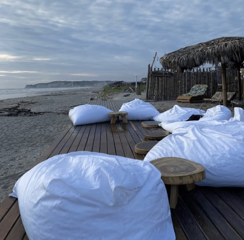 White bean bag chairs on wooden deck at Malù Surf Boutique Hôtel beach in Canoa, Ecuador