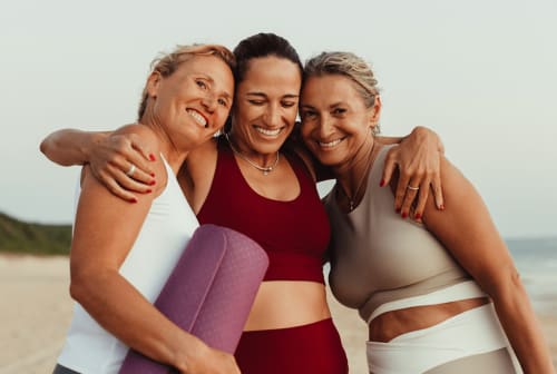 Three women smiling together at beach near Malù Surf Boutique Hôtel in Canoa