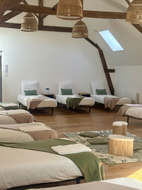 Dortoir spacieux de 14 lits au Domaine Du Grand Fort avec luminaires suspendus tressés et puits de lumière rustique
