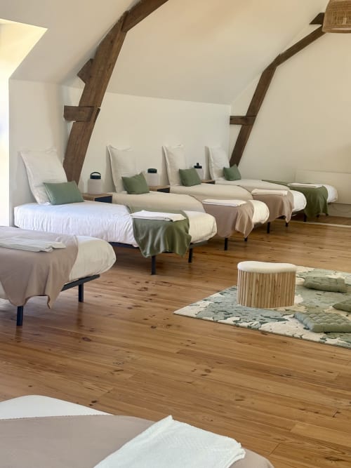 Chambre dortoir spacieuse au Domaine Du Grand Fort avec plusieurs lits, poutres en bois et vue sur le jardin