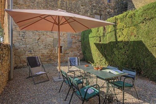 Patio de la casa rural Can Gat Vell en Girona, Cataluña con sombrilla, mesa y setos verdes