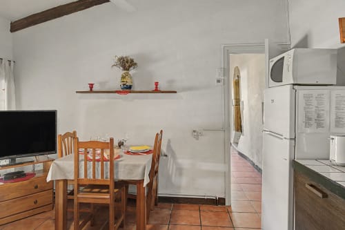 Cocina y comedor de Can Gat Vell, casa rural en Girona con mesa de madera, electrodomésticos blancos y viga rústica
