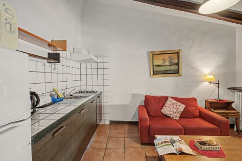 Estudio Can Gat Vell en Girona con cocina americana, sofá rojo y suelos de terracota