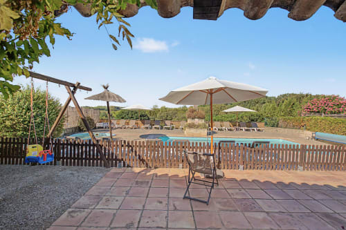 Terraza de jardín con sombrilla, tumbona y vistas a la piscina en la casa Can Gat Vell en Saus, España