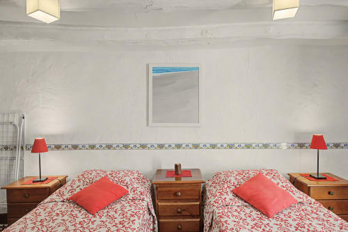 Dormitorio doble con ropa de cama roja con estampados y lámparas en la casa rural Can Gat Vell, Saus, España