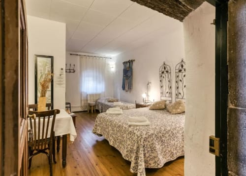 Dormitorio espacioso en la casa rural Can Gat Vell con camas gemelas, vigas rústicas y decoración tradicional en Saus, España