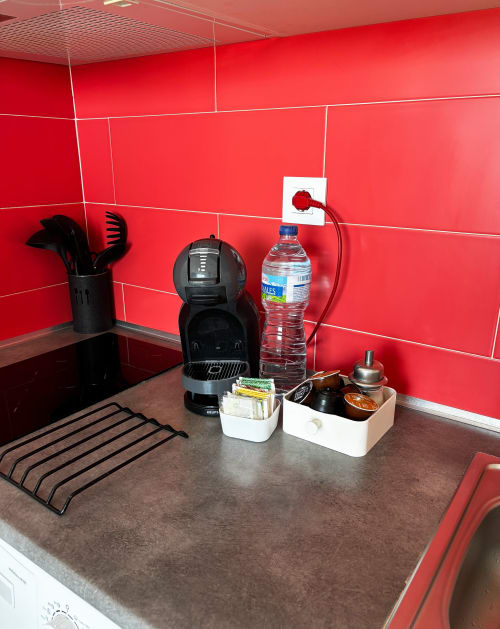 Rincón moderno de cocina con azulejos rojos, cafetera, botella de agua y encimera organizada en La Ventana