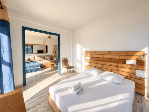 Chambre moderne avec tête de lit en bois, literie blanche et vue sur mer, propriété Century 21 à L'Île-Rousse, Corse