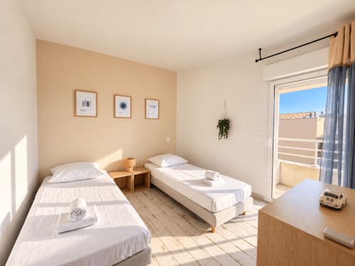 Chambre double lumineuse dans l'appartement de L'Île-Rousse avec balcon vue mer, mobilier en bois et équipements modernes