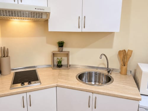Cocina moderna en apartamento de Baiona con vitrocerámica, fregadero redondo, encimeras de madera y armarios blancos