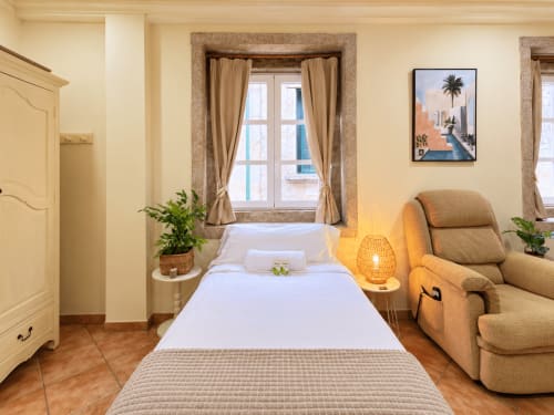 Apartamento estudio luminoso en Baiona con cama individual, butaca beige, vistas a la ciudad y comodidades modernas como TV y WiFi