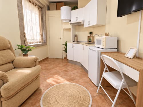 Estudio compacto en Baiona con cocina americana, escritorio, butaca beis y televisor