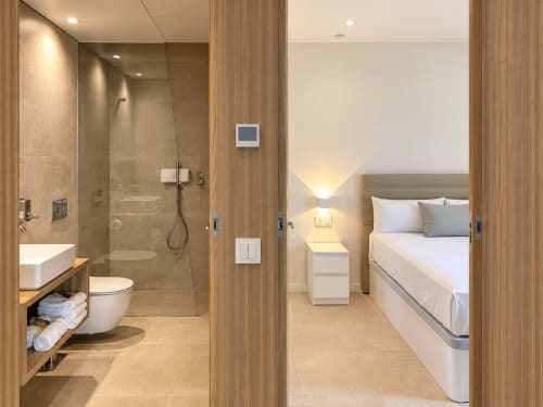 Dormitorio y baño moderno en apartamento Holibai, Baiona, con acabados en madera, ducha, cama y servicios