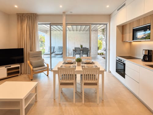 Amplia sala de estar de planta abierta en apartamento Holibai de Baiona con comedor, cocina, acceso a terraza y vistas al jardín
