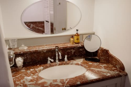 Elegant bathroom vanity in Thérèse Suite at Castanea Business & Suites with marble countertop, undermount sink, and round