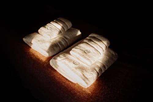 Rolled white towels with twine on warm-lit surface at Castanea Business & Suites, Merelbeke
