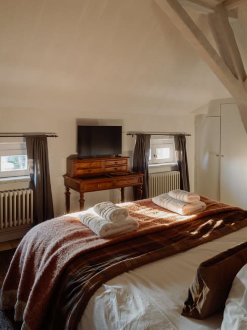 Thérèse Suite bedroom at Castanea Business & Suites with elegant wooden desk, white rolled towels, and garden views in