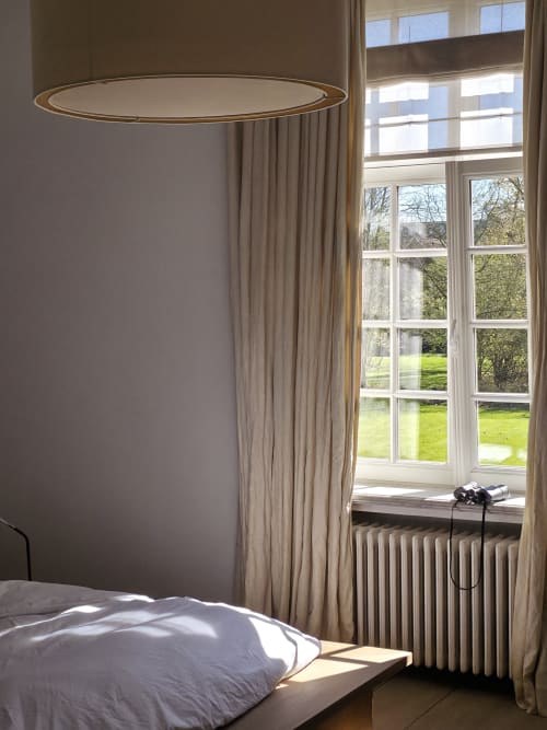 Bernard Suite bedroom at Castanea Business & Suites with garden view, modern pendant light, and large windows overlooking