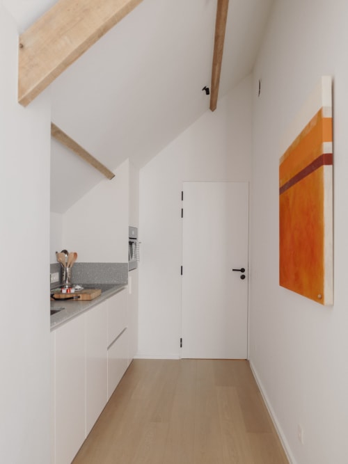 Modern kitchen in Studio Fabienne at Castanea Business & Suites, featuring white cabinetry, gray countertop, and orange