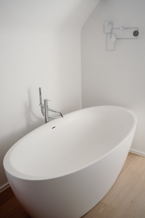 Modern white freestanding bathtub with floor faucet in Studio Fabienne apartment at Castanea Business & Suites, Merelbeke