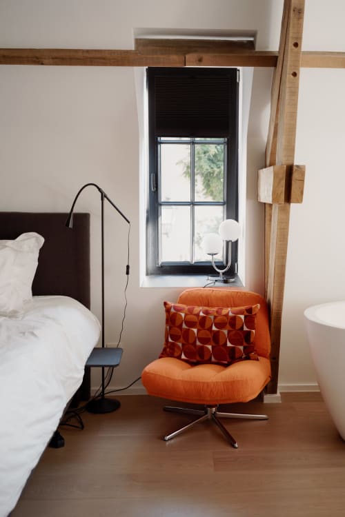 Studio Fabienne at Castanea Business & Suites in Merelbeke features a bed, orange accent chair, and modern window with black