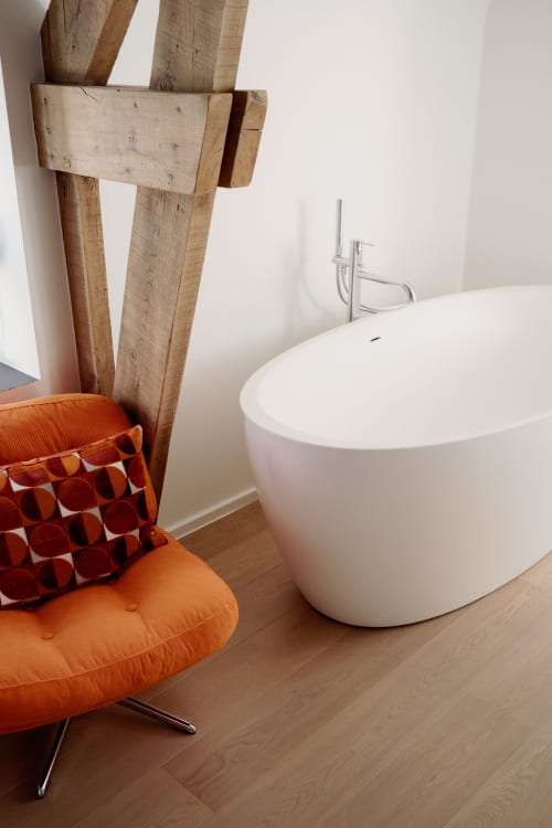 Modern bathroom at Castanea Studio Fabienne with white soaking tub, wooden accent wall, and orange lounge chair