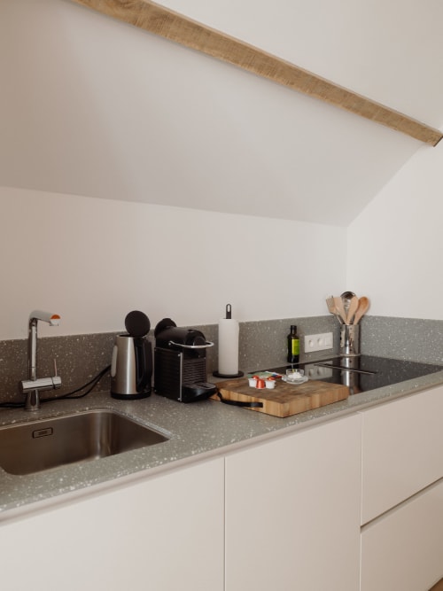 Modern kitchen in Studio Fabienne at Castanea Business & Suites with stainless steel sink, gray speckled countertop, and