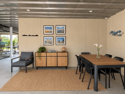 Moderna zona de comedor y sala de estar del apartamento Holibai en Baiona con mesa de madera, sillas negras, sillón gris y vistas al jardín