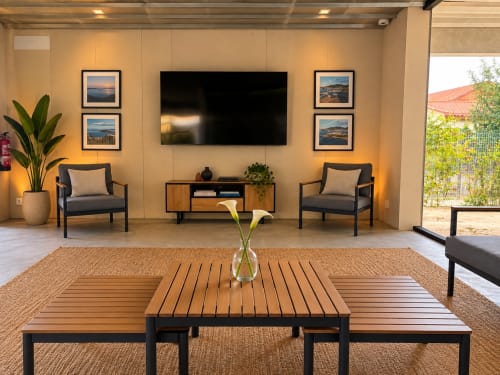 Elegante sala de estar moderna con televisor, cuadros decorativos, zona de descanso y vistas al jardín del hotel Holibai en Baiona